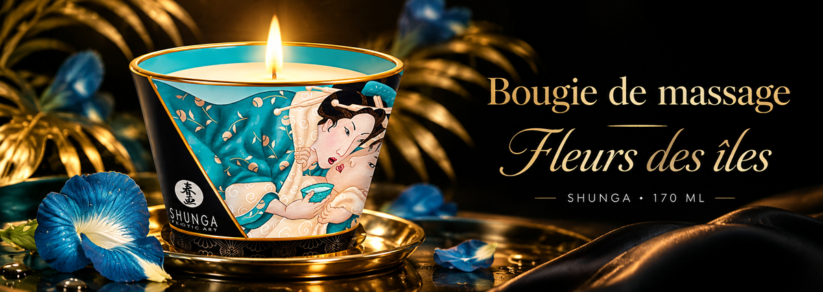 Bannière de la bougie de massage Shunga Fleurs des Îles 170 ml, présentée allumée dans une ambiance luxueuse noire et dorée, avec des fleurs tropicales bleues, des feuillages dorés et une élégante étoffe satinée.