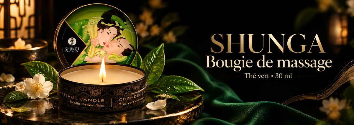 Bannière de la bougie de massage Shunga Mini Caress Thé Vert 30 ml, présentée allumée dans une ambiance luxueuse noire, verte et dorée, entourée de feuilles de thé et de fleurs blanches.