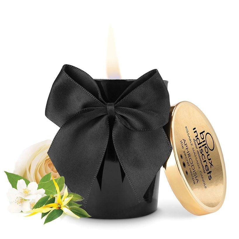 Bougie de massage Melt My Cœur Aphrodisia Bijoux Indiscrets allumée, pot noir, nœud satiné et couvercle doré