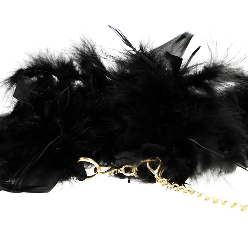 Gros plan sur les plumes noires et l'attache de la chaîne dorée des menottes de luxe