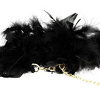 Gros plan sur les plumes noires et l'attache de la chaîne dorée des menottes de luxe